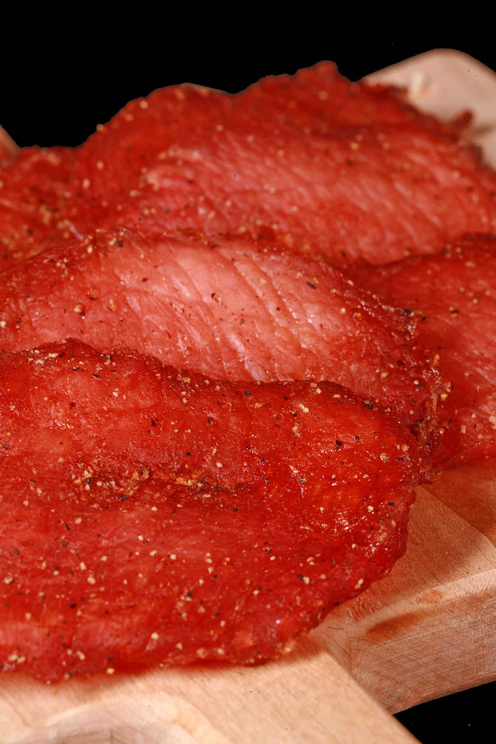 A close up photo of a pile of back bacon pork jerky slices.