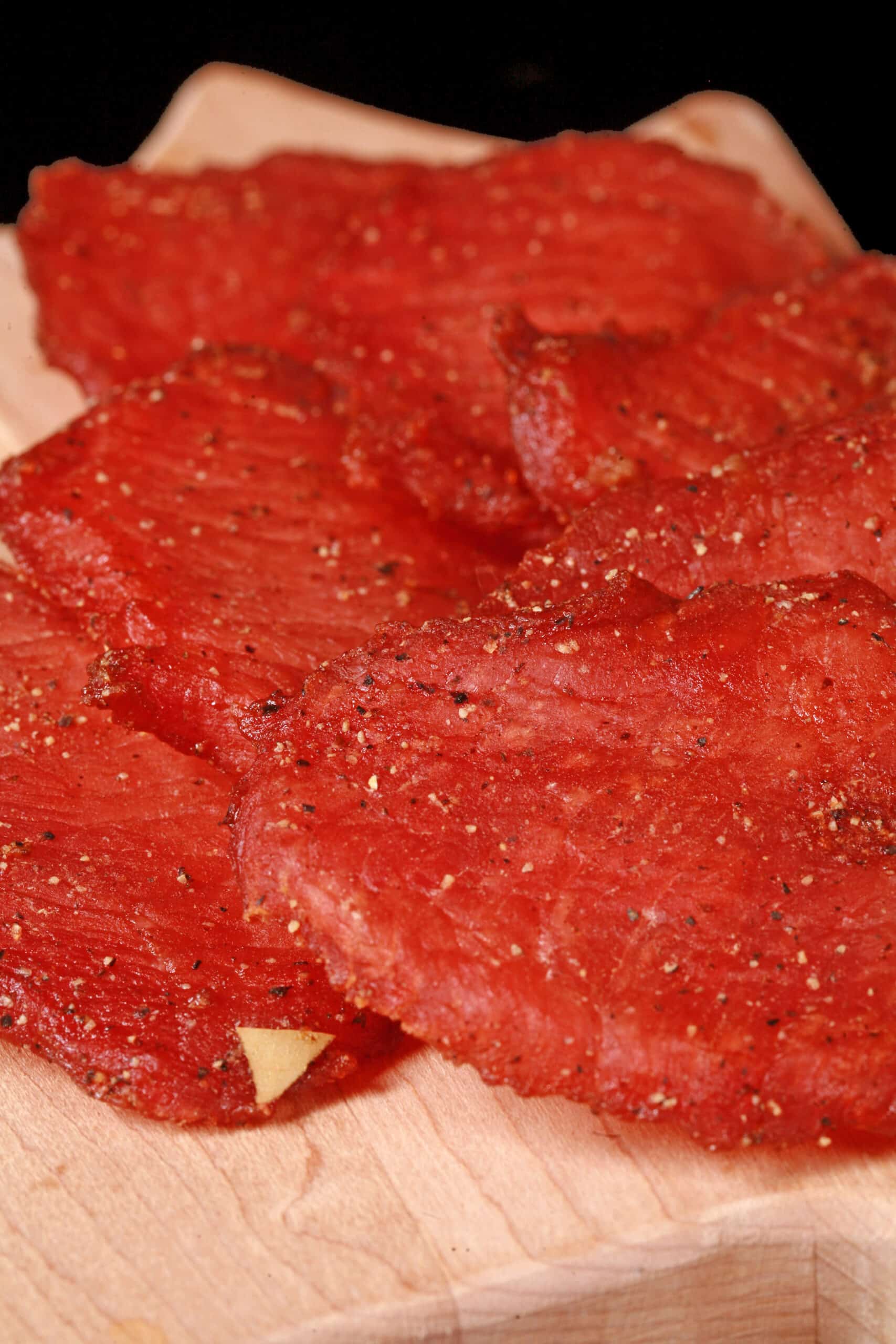 A close up photo of a pile of back bacon pork jerky slices.