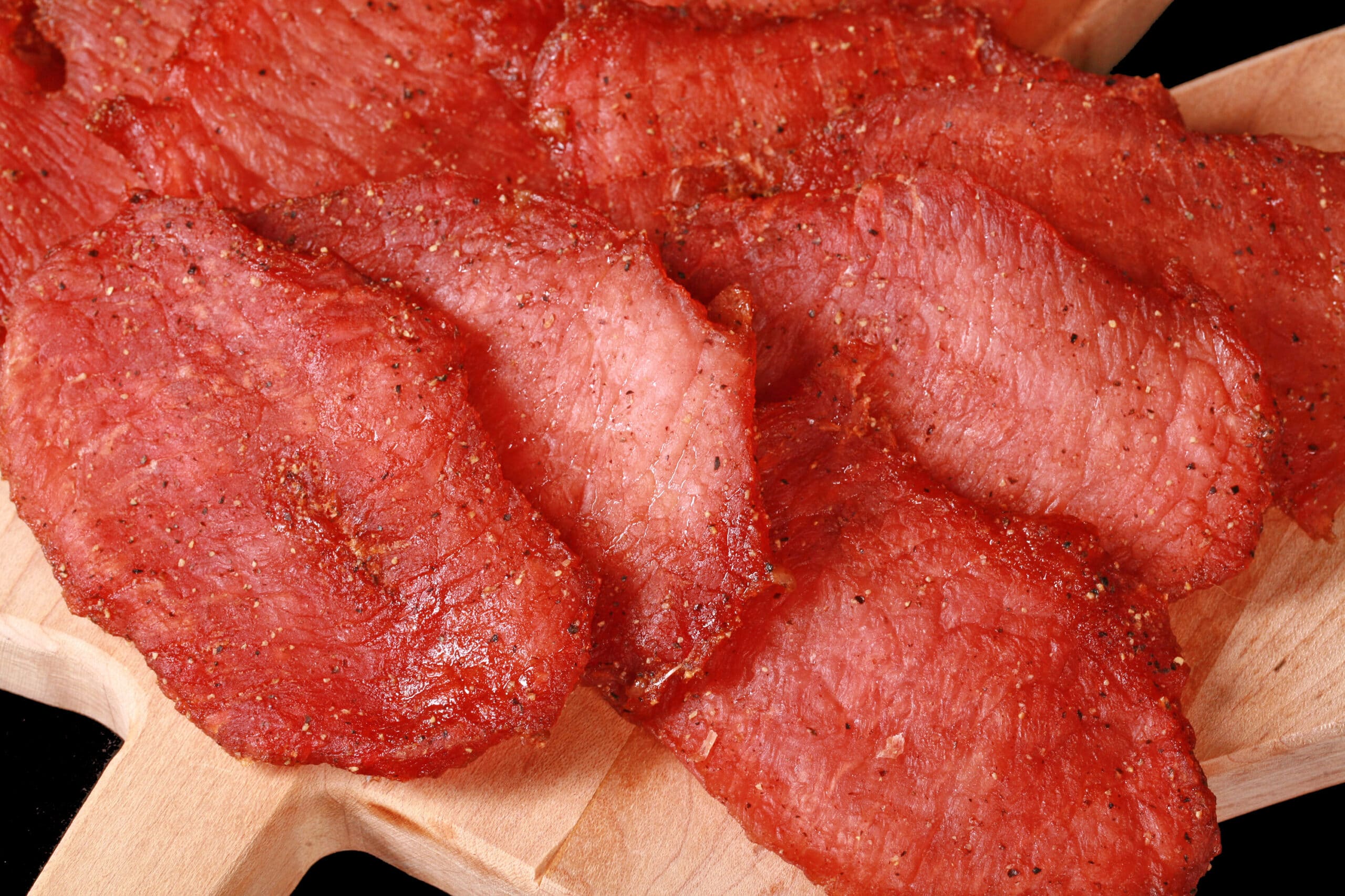A close up photo of a pile of back bacon pork jerky slices.