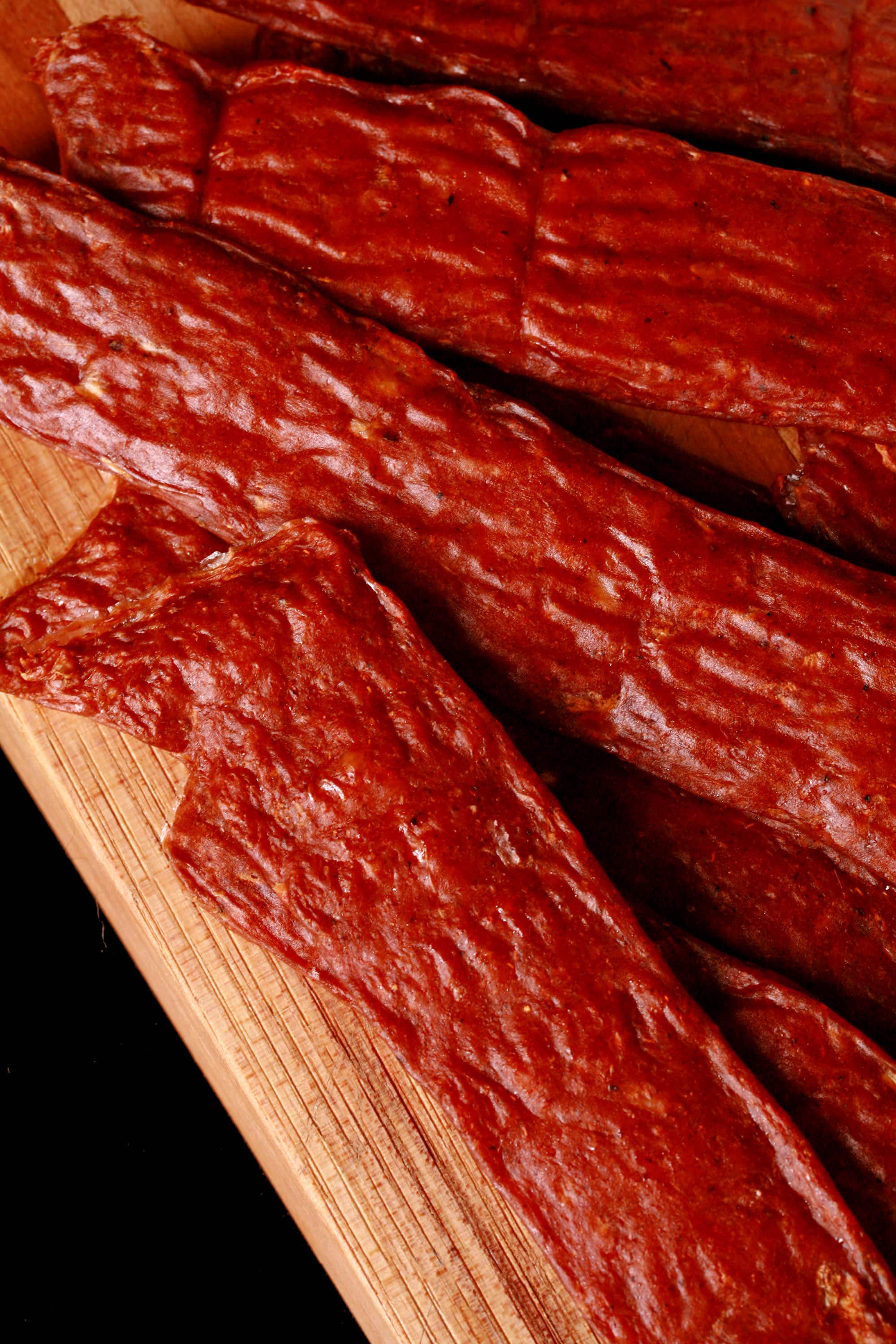 Several strips of berbere ground chicken jerky on a cutting board with a ramekin of berbere seasoning.