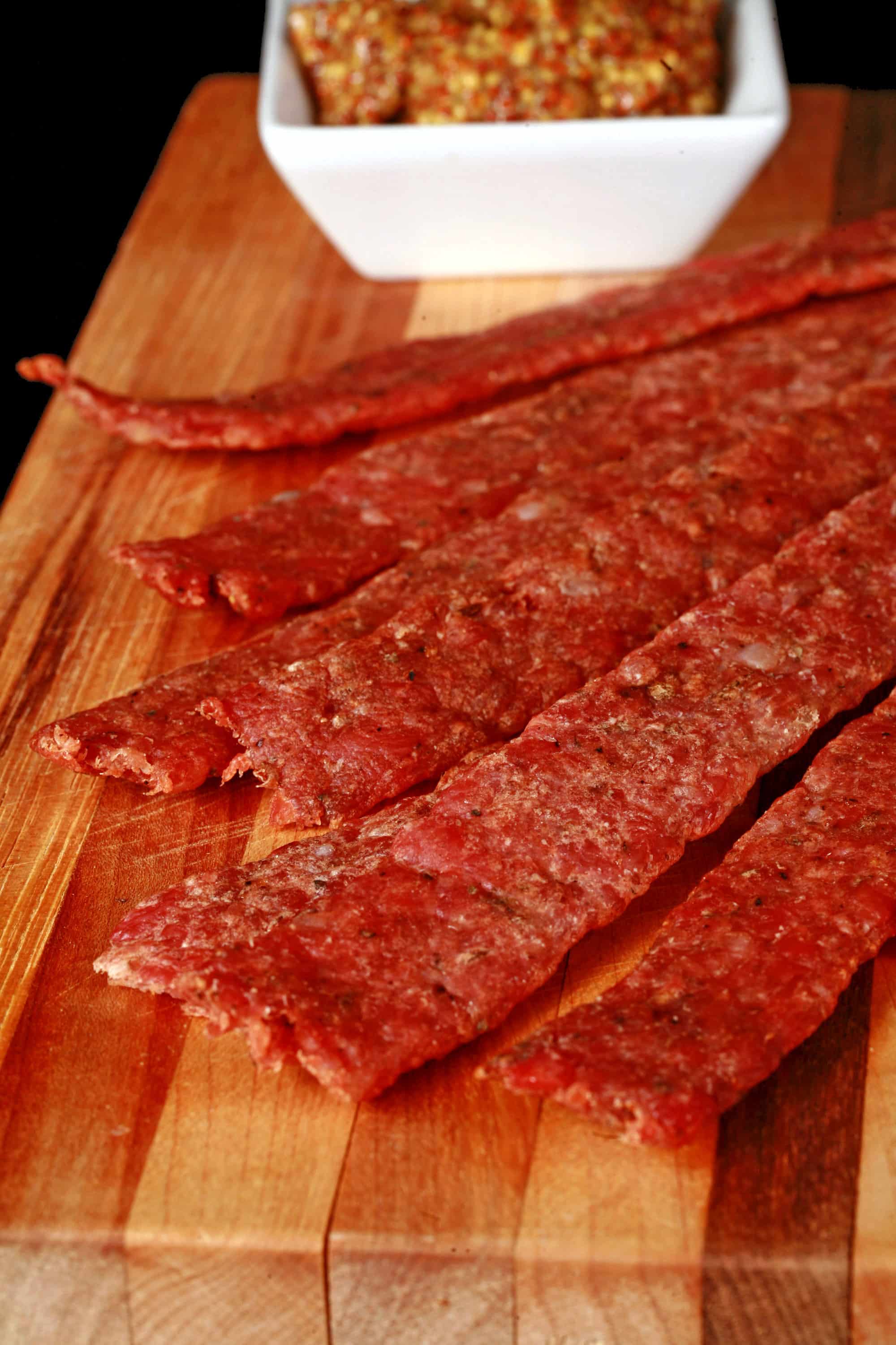 Several strips of bratwurst jerky on a cutting board.