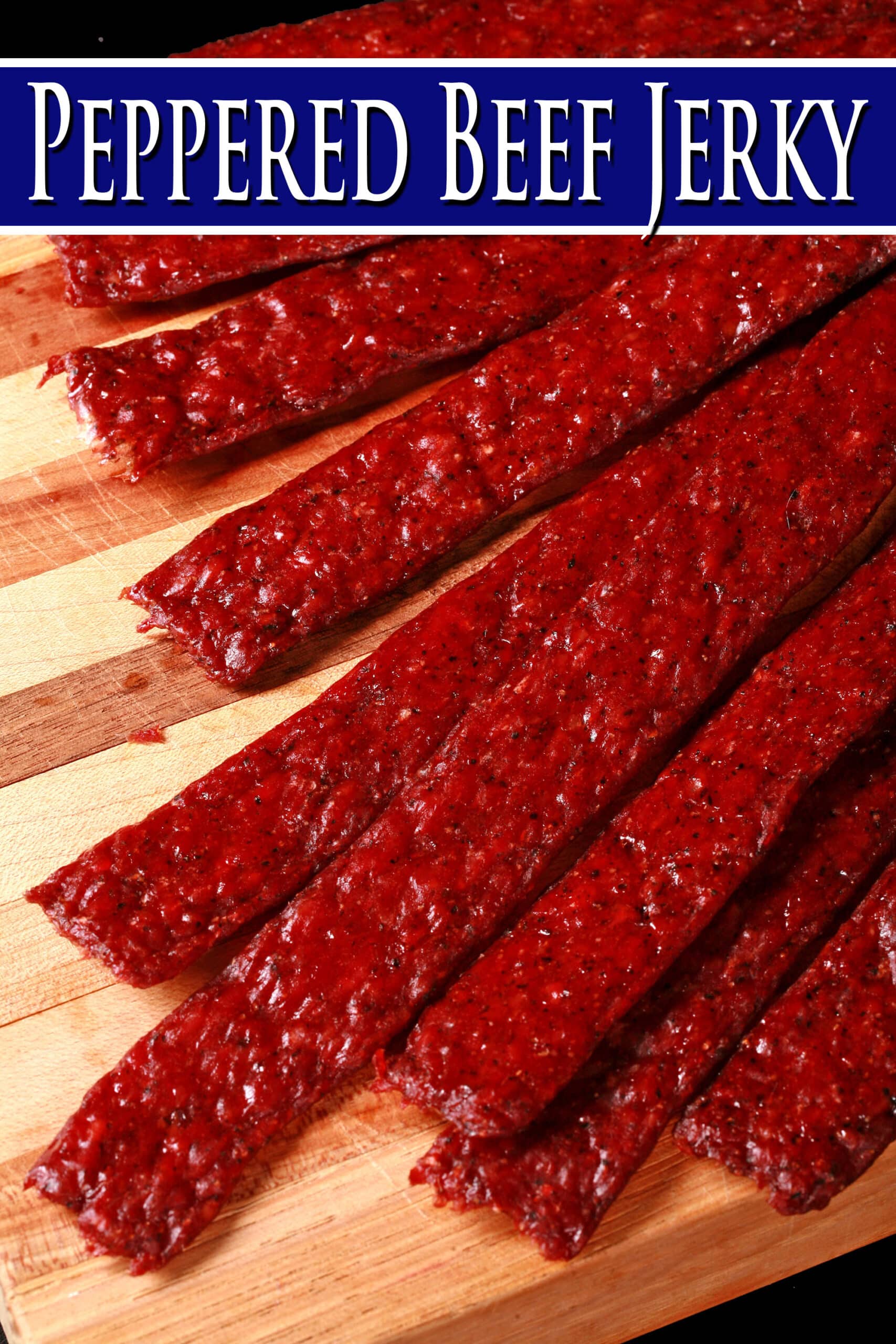 Several strips of homemade peppered ground beef jerky on a wooden cutting board. Overlaid text says peppered beef jerky.
