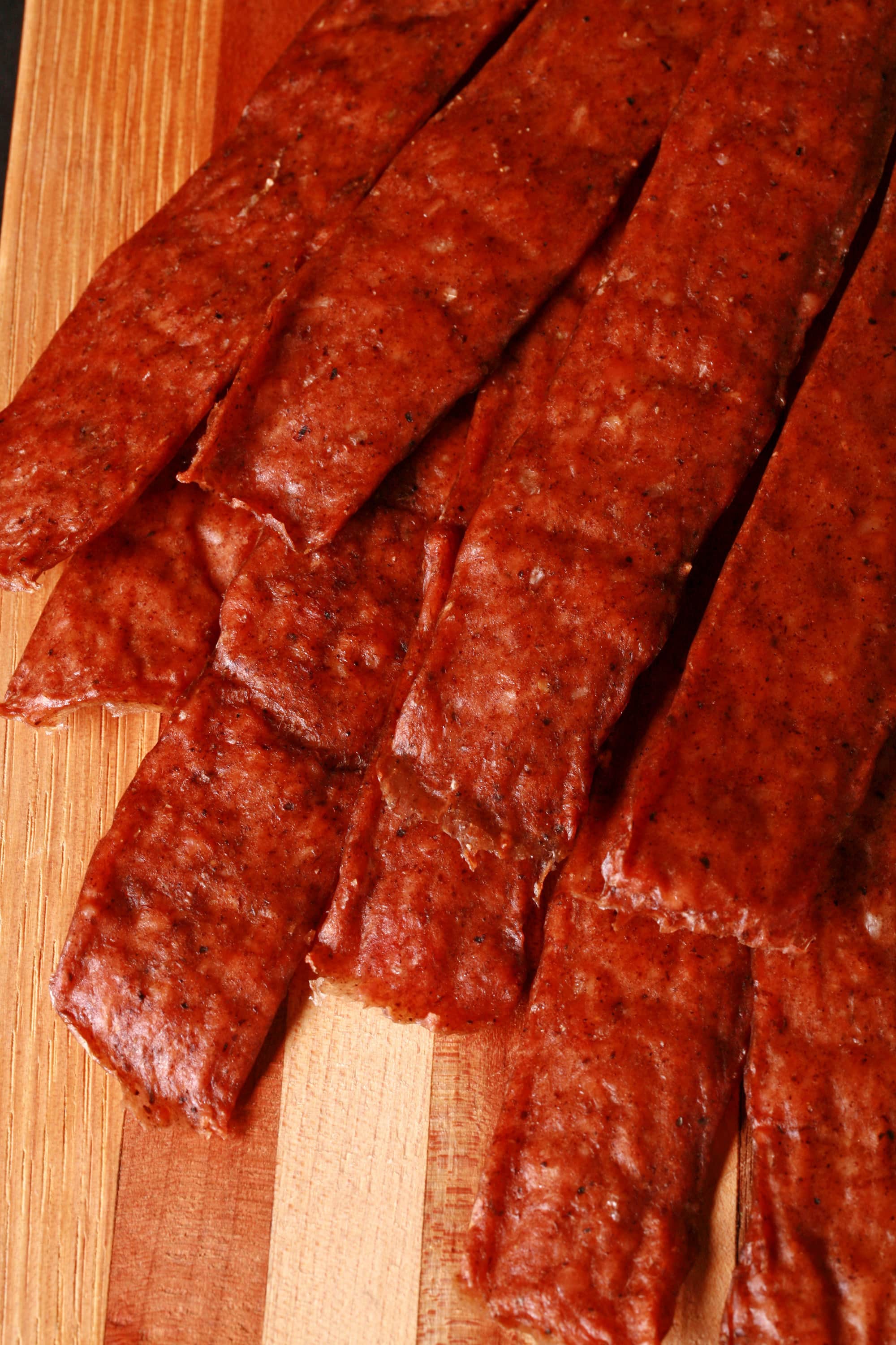 Several strips of swedish potato sausage jerky on a cutting board.