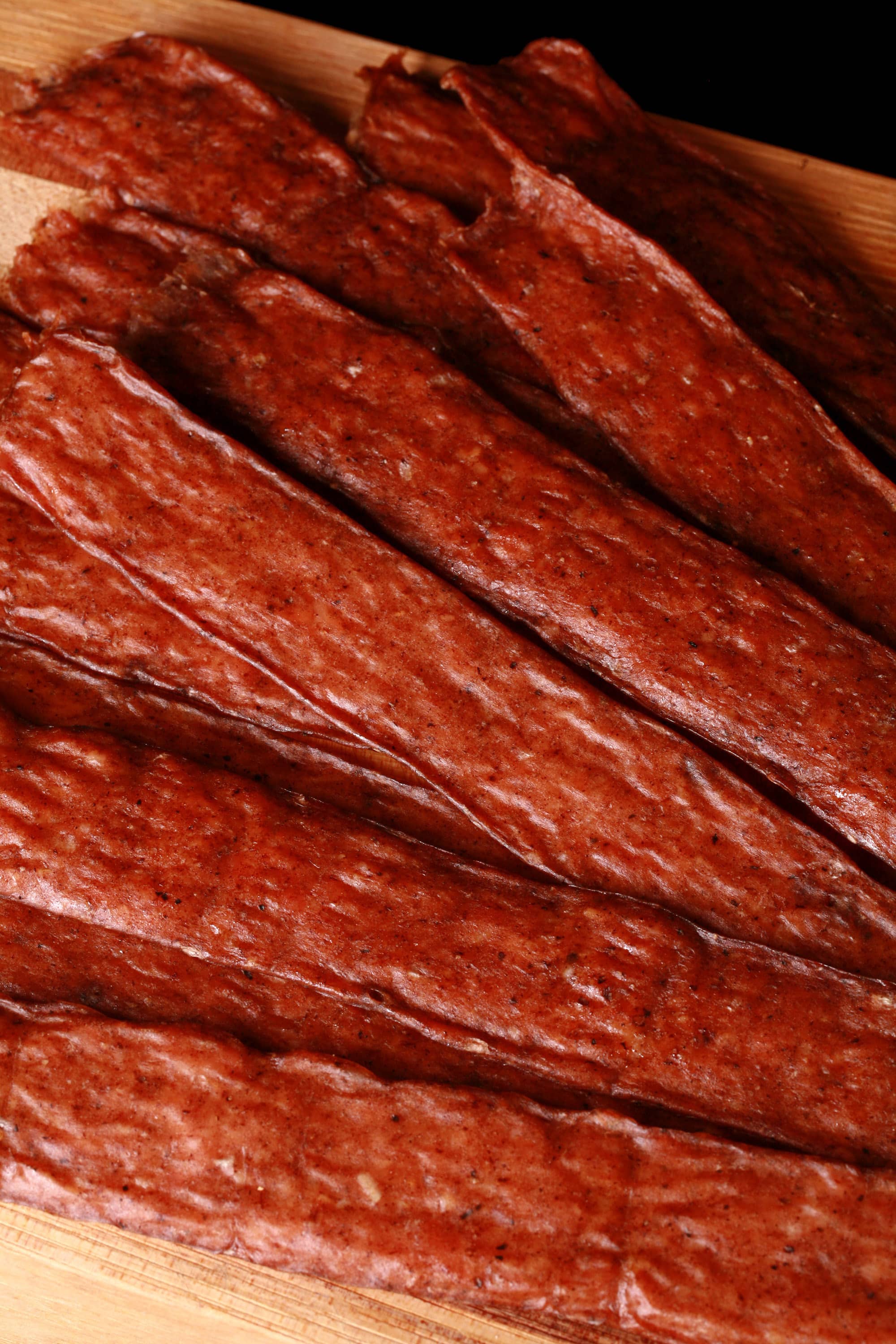 Several strips of swedish potato sausage ground chicken jerky on a cutting board.