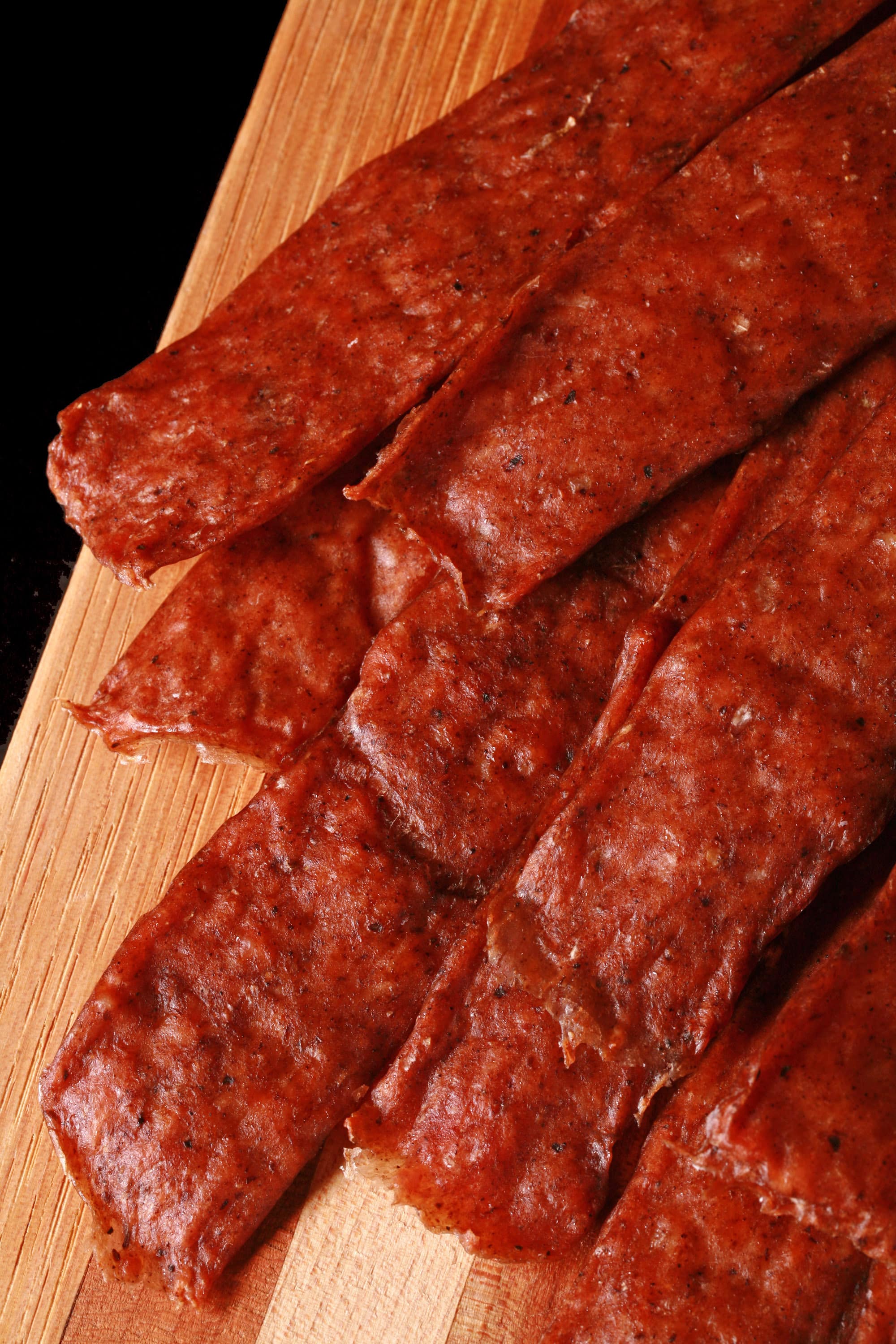 Several strips of swedish potato sausage jerky on a cutting board.