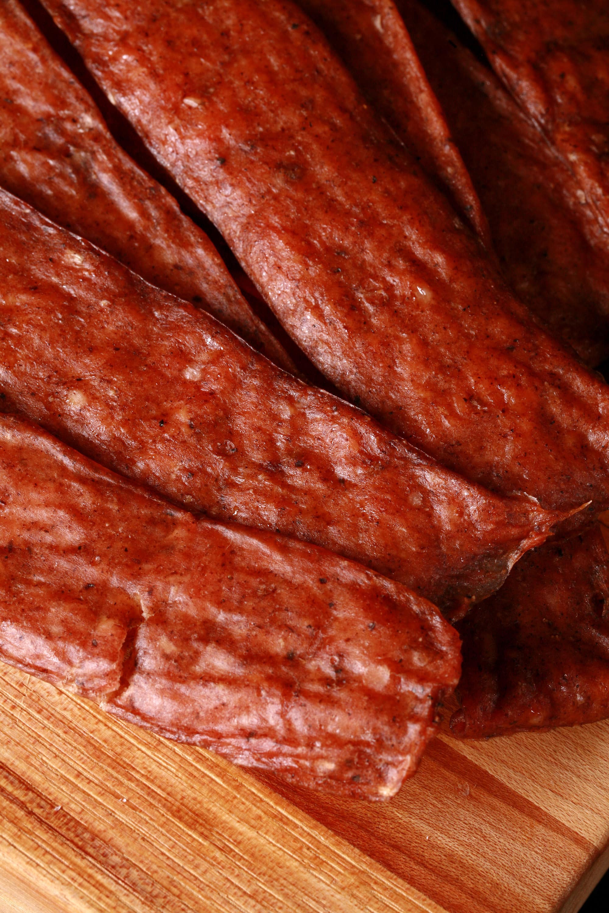 Several strips of swedish potato sausage ground chicken jerky on a cutting board.