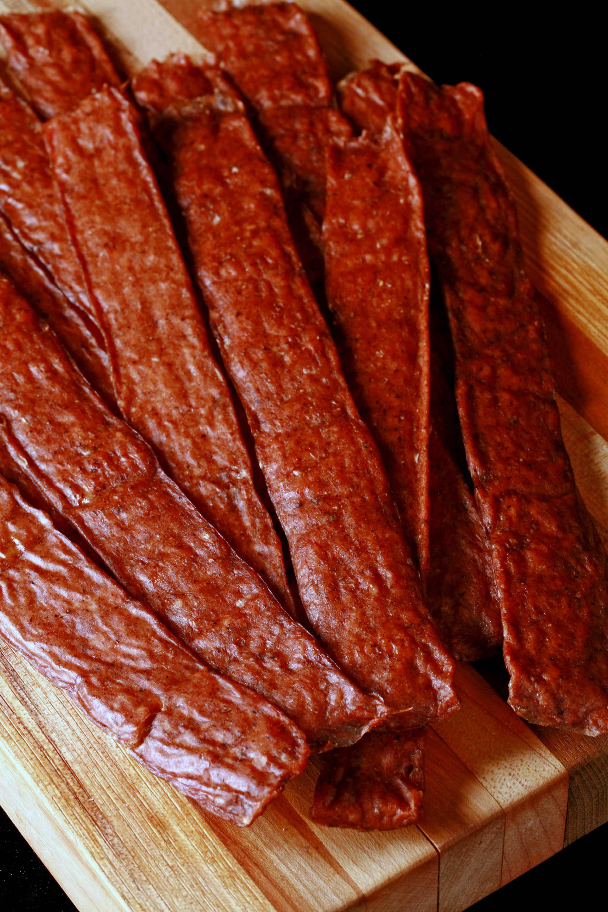 Several strips of swedish potato sausage jerky on a cutting board.