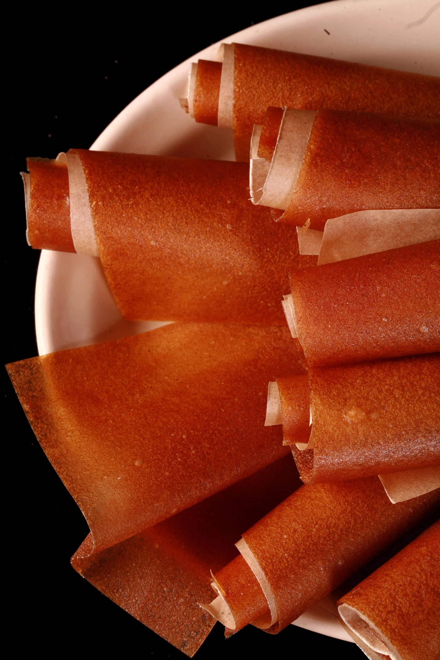 A plate of homemade apple cinnamon fruit leather rolls.