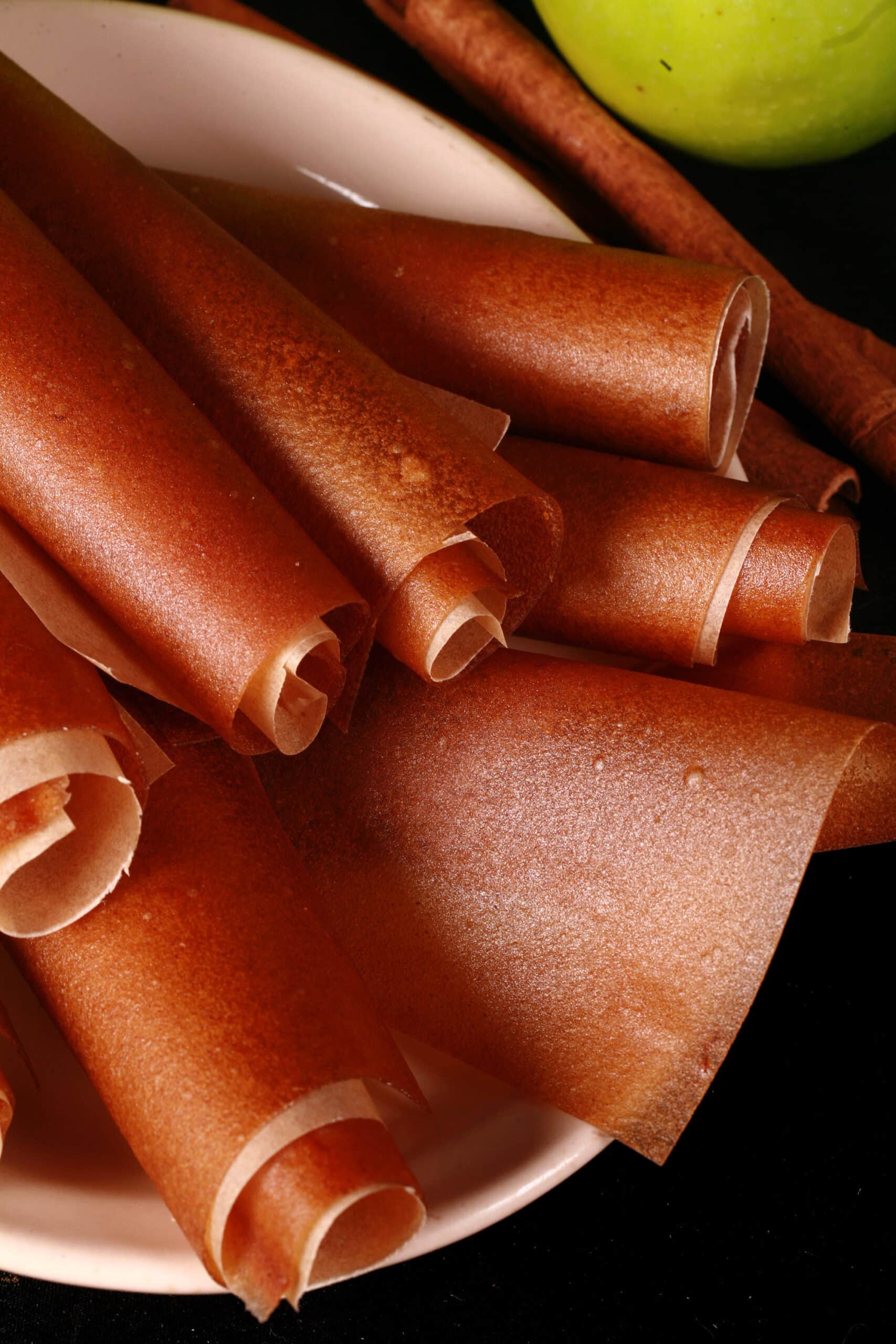 A plate of homemade apple cinnamon fruit leather rolls.