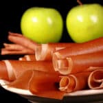 A plate of homemade apple cinnamon fruit leather rolls.