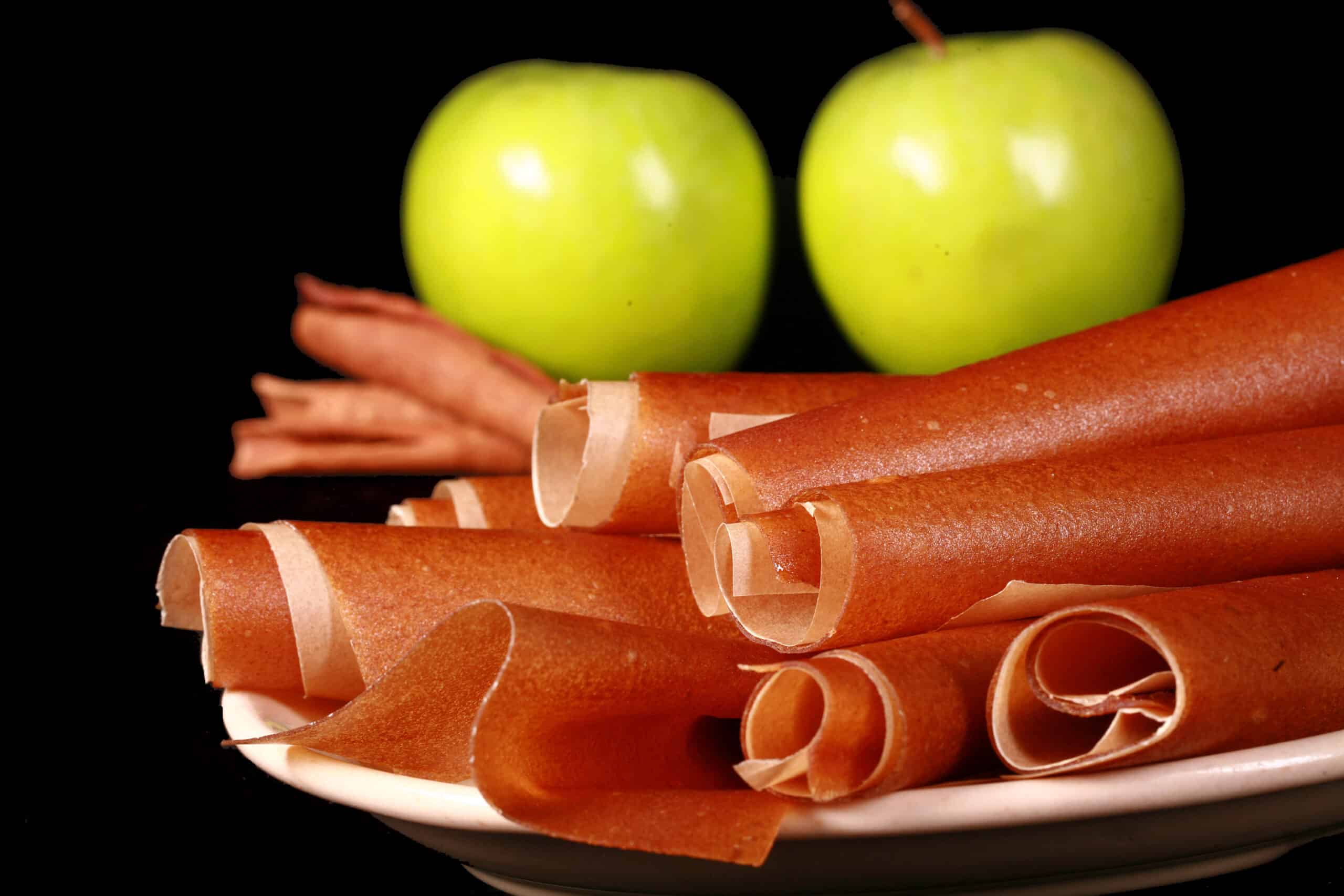 A plate of homemade apple cinnamon fruit leather rolls.
