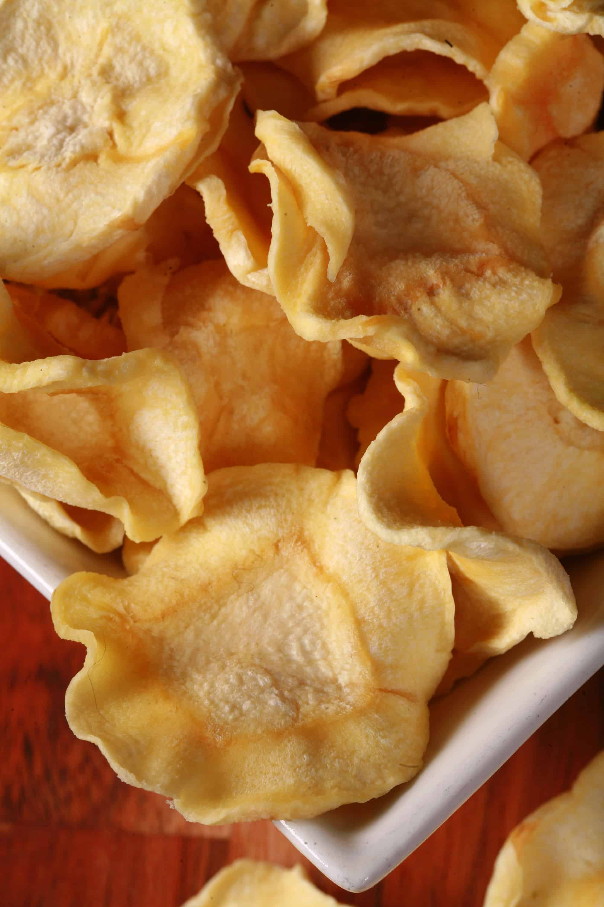 A bowl of crispy dehydrated parsnip chips.