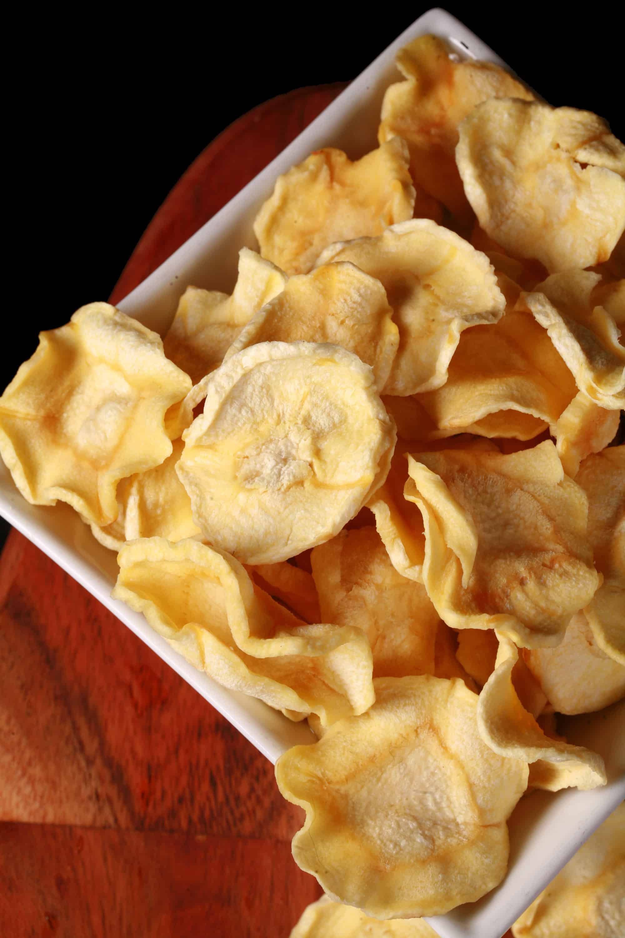 A bowl of crispy dehydrated parsnip chips.