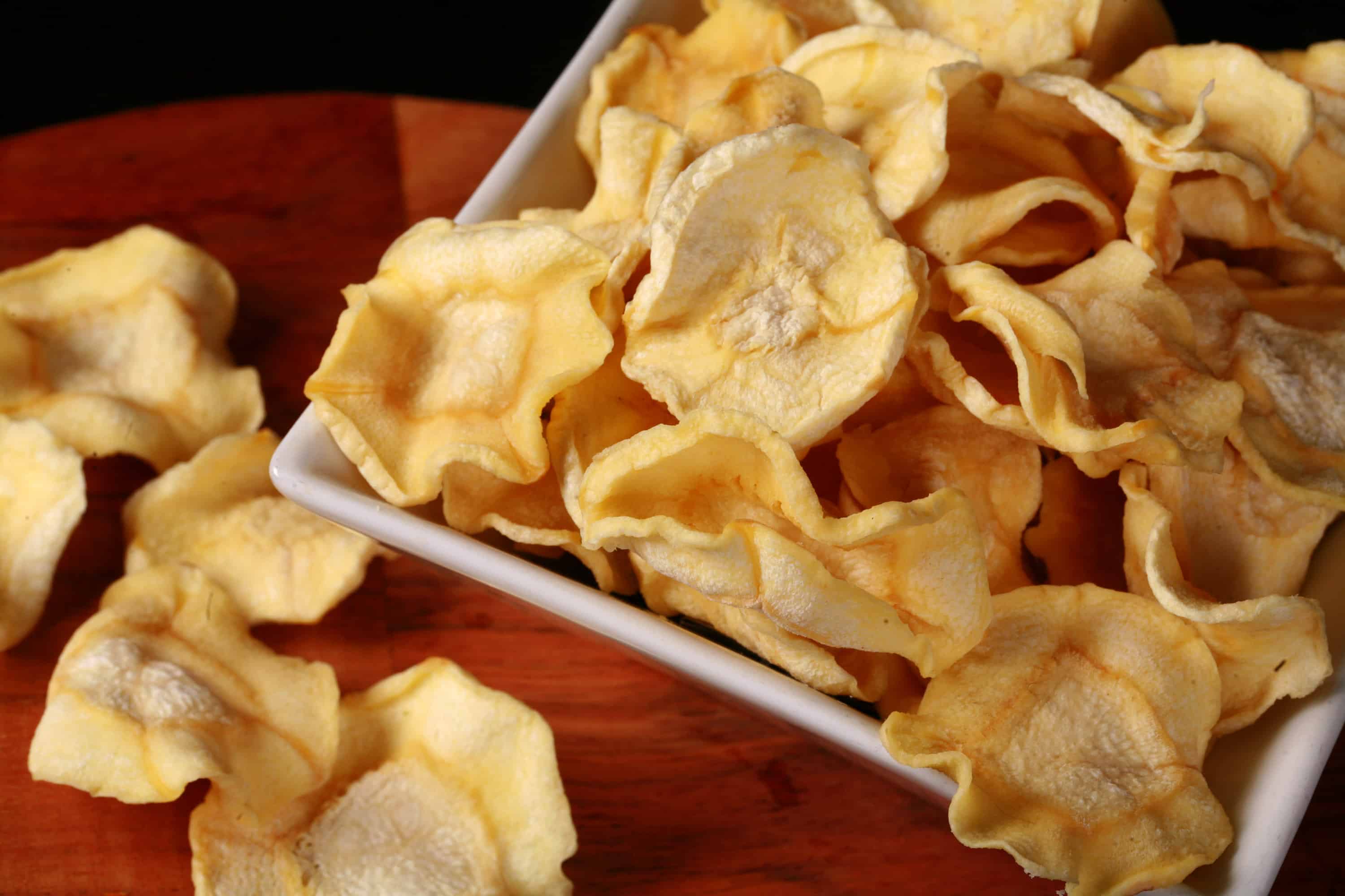 A bowl of crispy dehydrated parsnip chips.