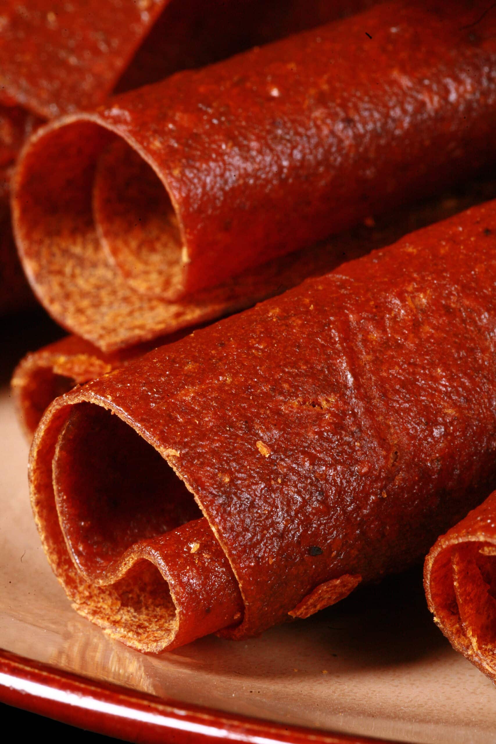 A plate with several rolls of pumpkin fruit leather.