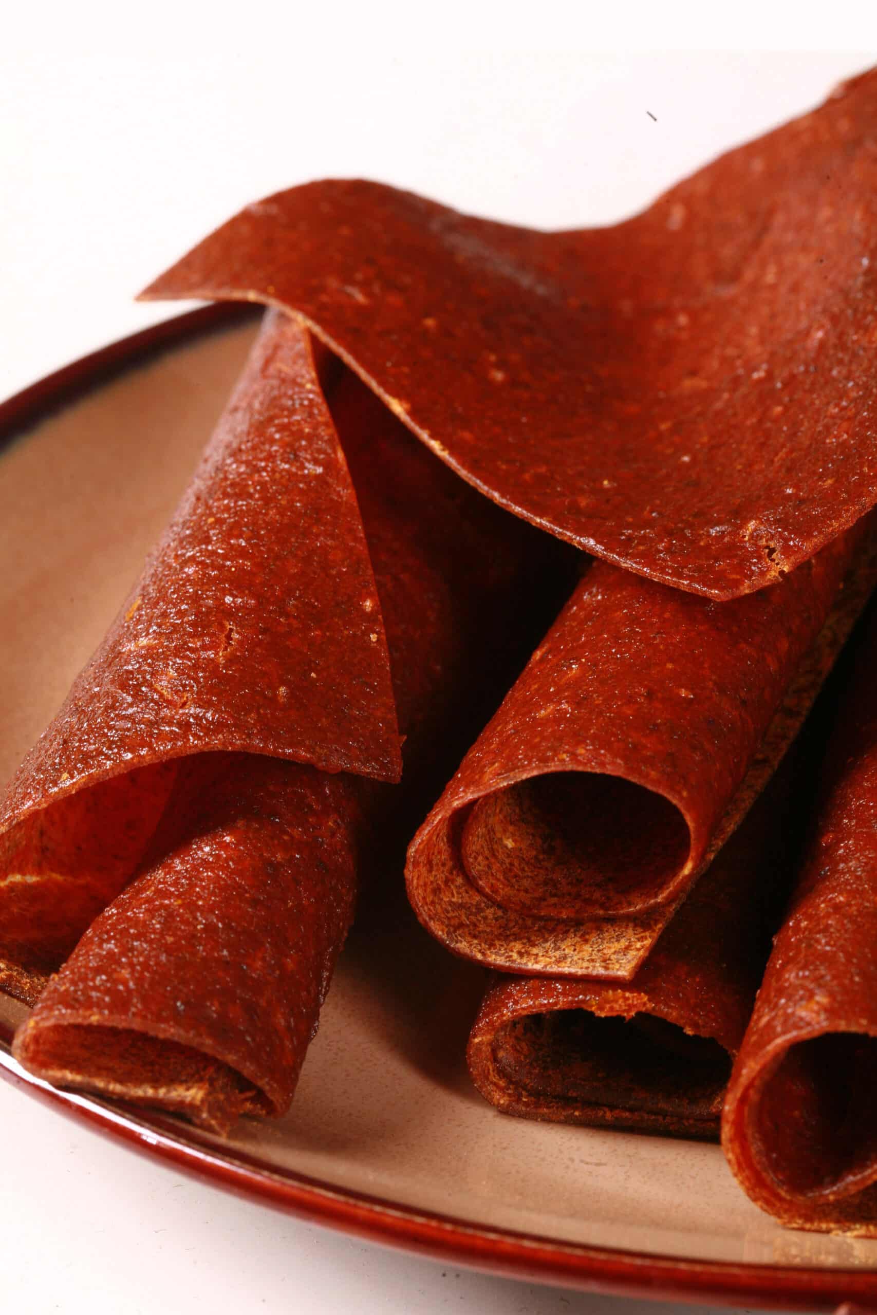 A plate with several rolls of pumpkin fruit leather.