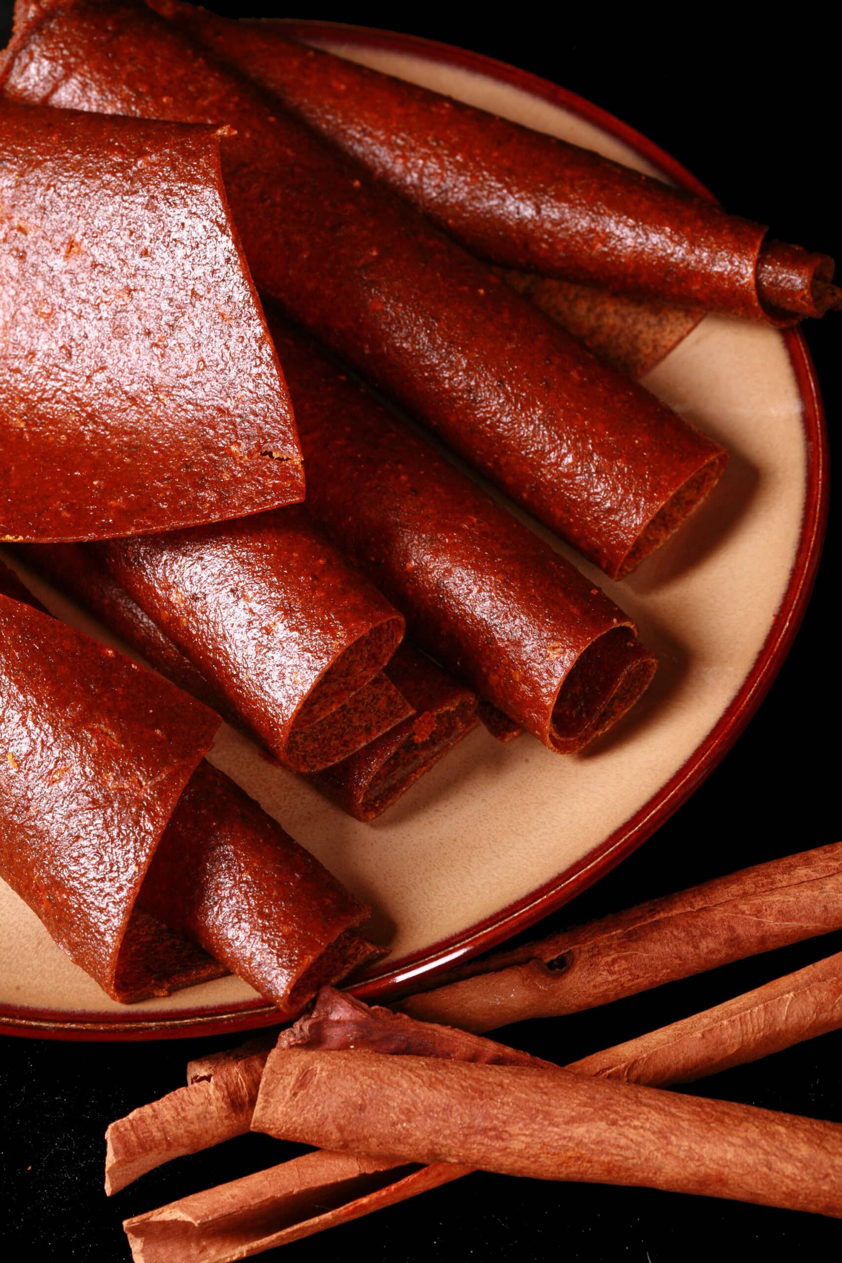 A plate with several rolls of pumpkin spice fruit leather.