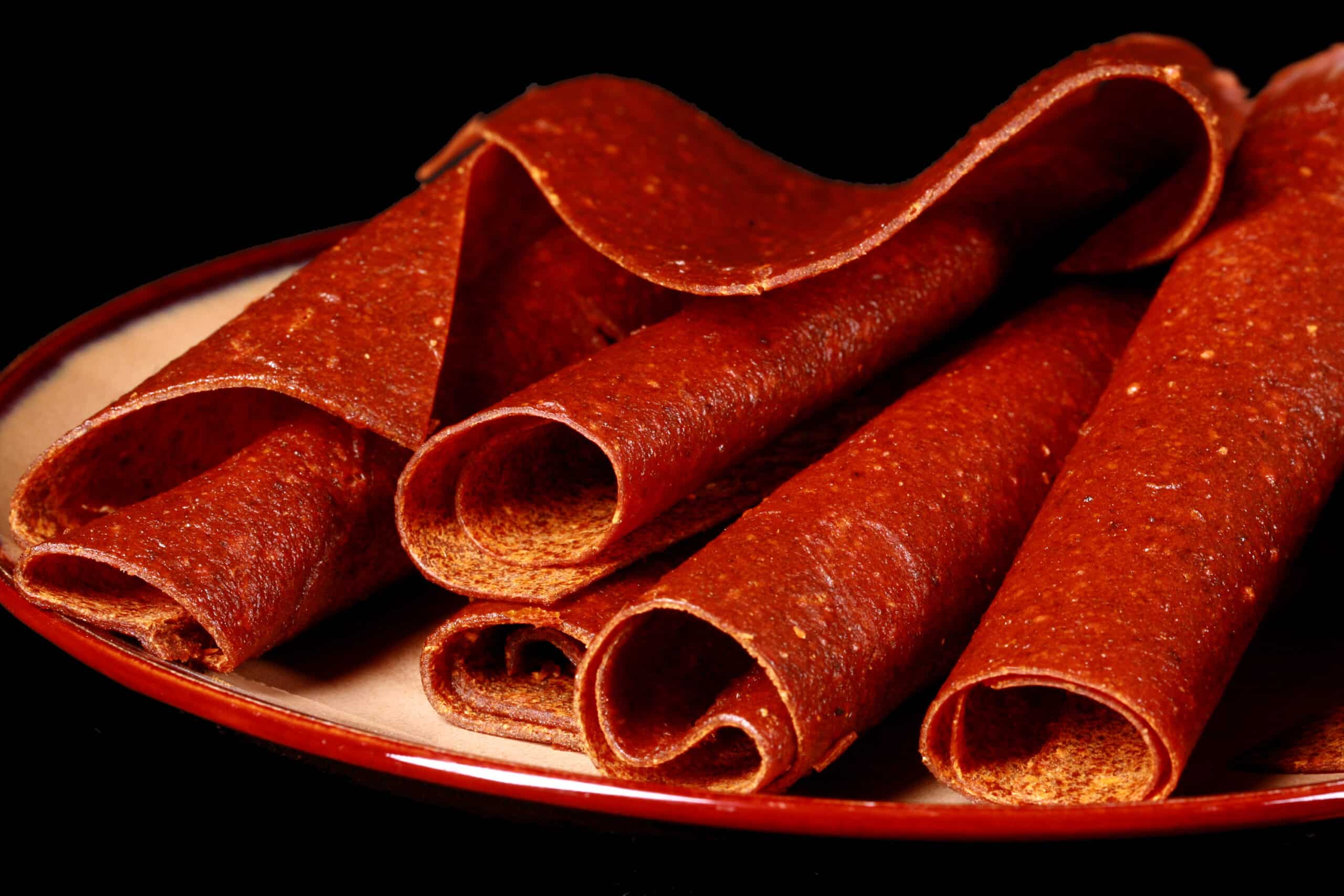 A plate with several rolls of pumpkin spice fruit leather.