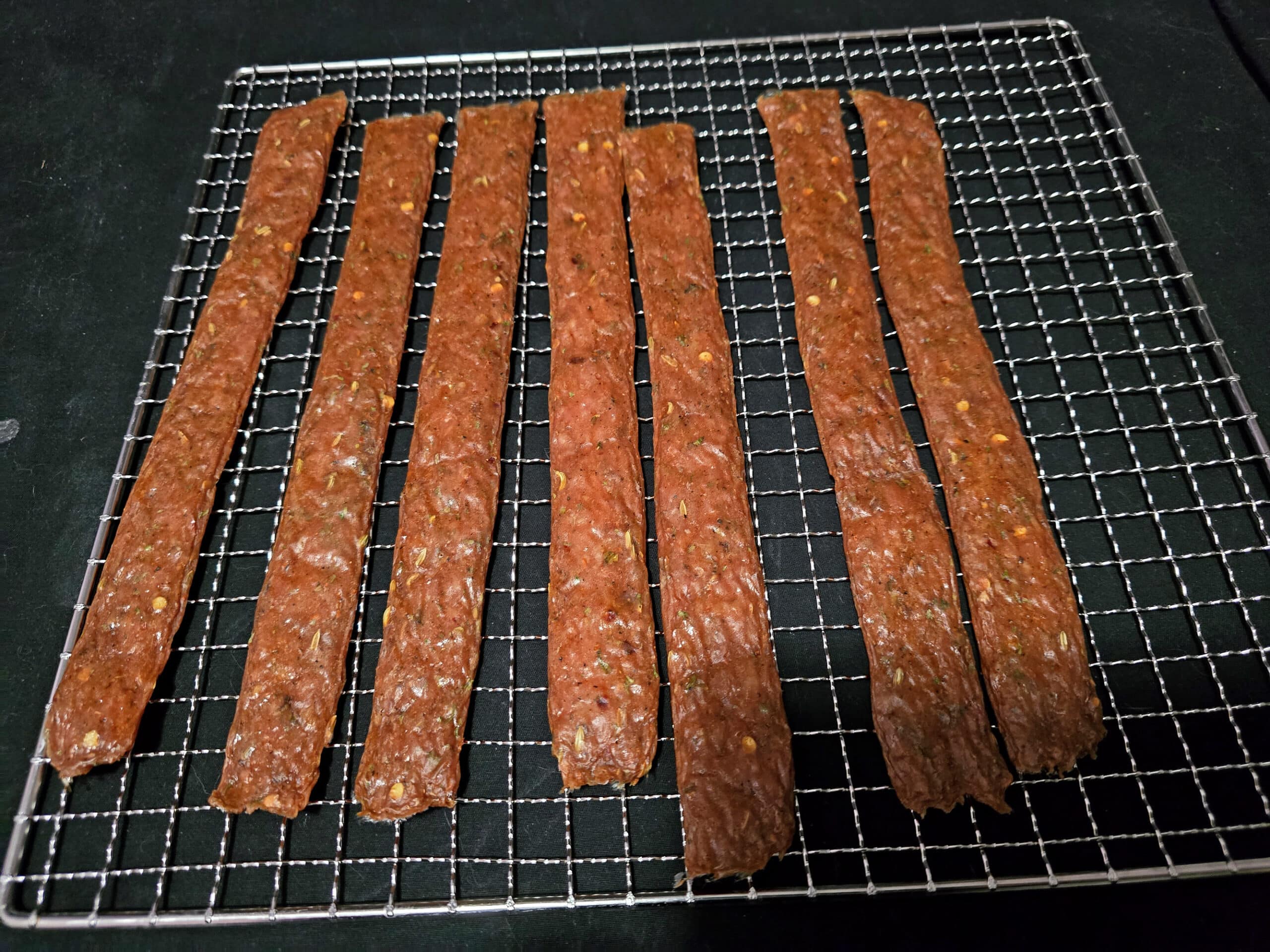 A rack of finished spicy Italian Sausage jerky.