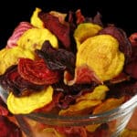 A bowl of golden, striped, and red dehydrated beet chips.
