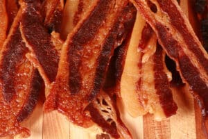 A small pile of homemade maple bacon jerky on a cutting board.