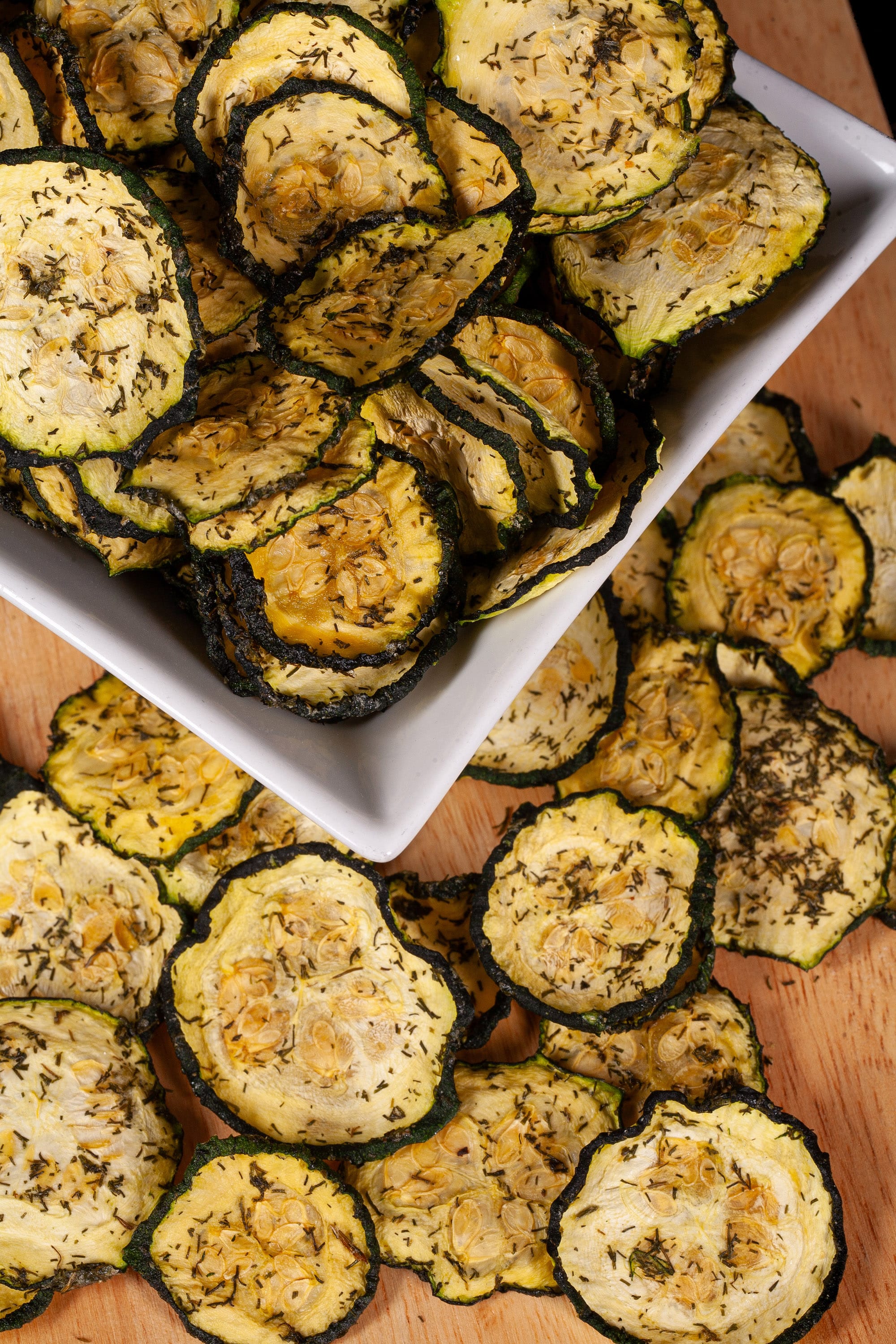 A pile of homemade dill pickle zucchini chips on a cutting board.