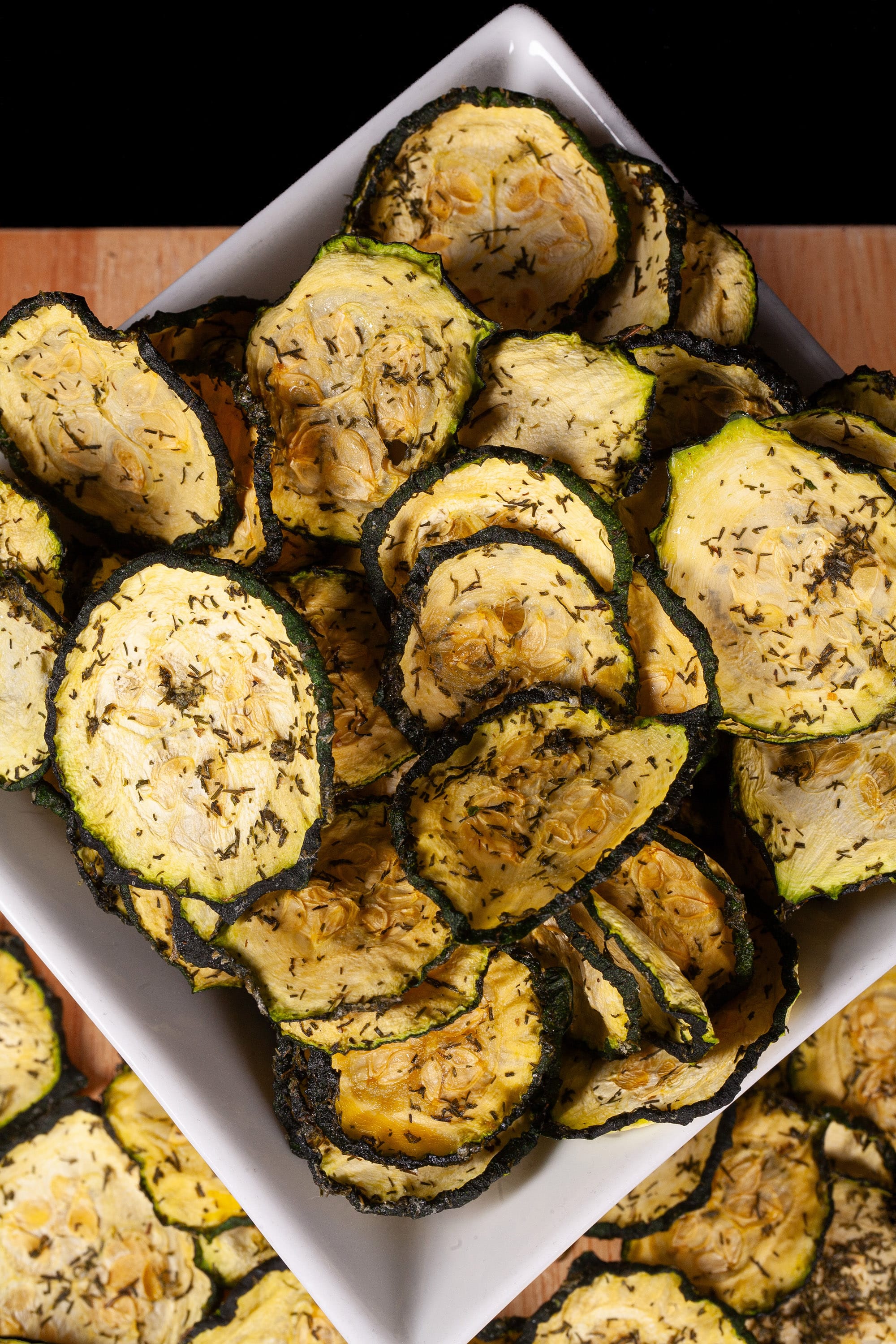 A pile of homemade dill pickle zucchini chips on a cutting board.