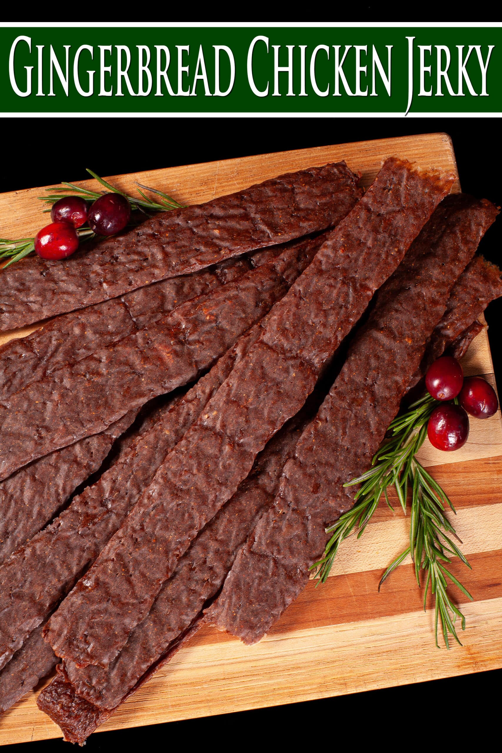 Several strips of gingerbread jerky on a wooden cutting board with rosemary and cranberries. Overlaid text says gingerbread chicken jerky.