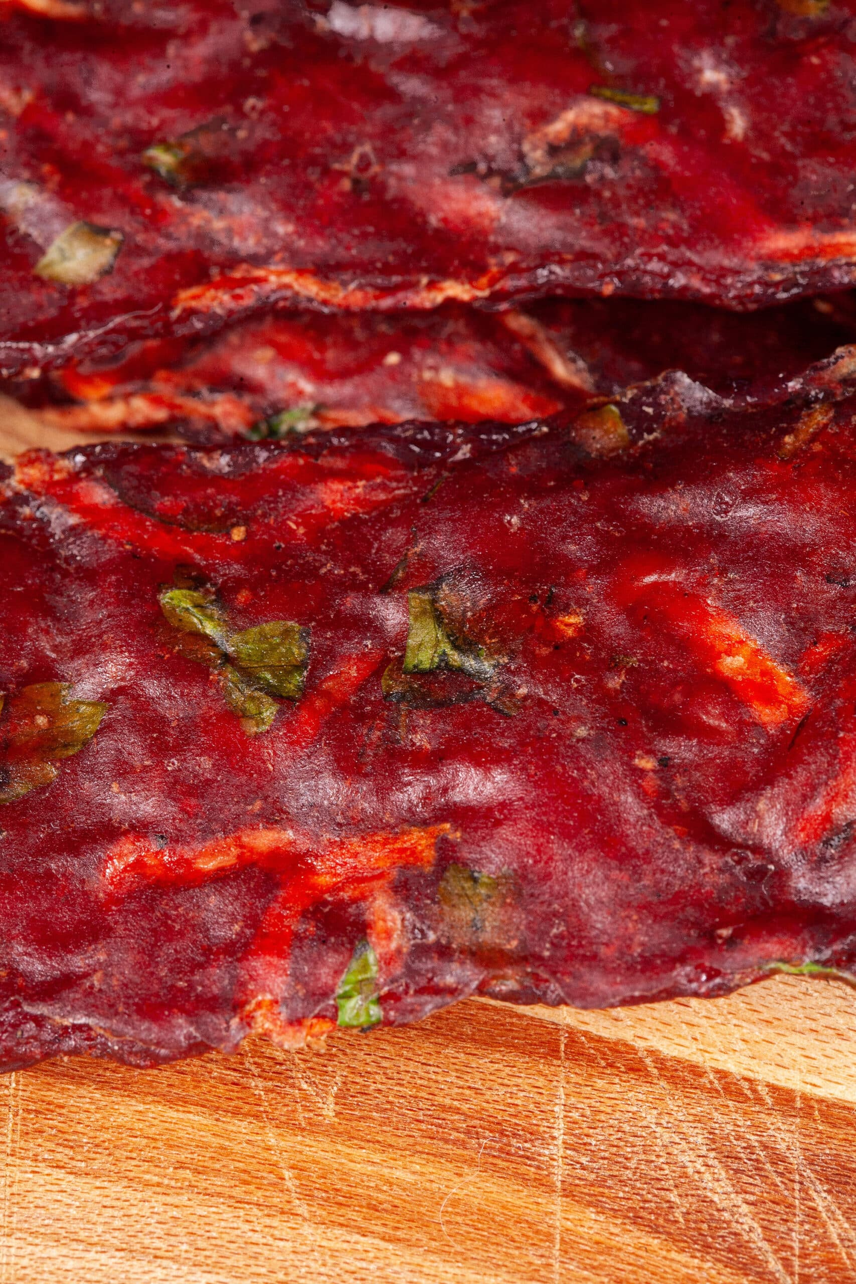 Several strips of Irish Stew jerky on a cutting board, with carrots, turnips, and parsley visible in the homemade beef jerky.
