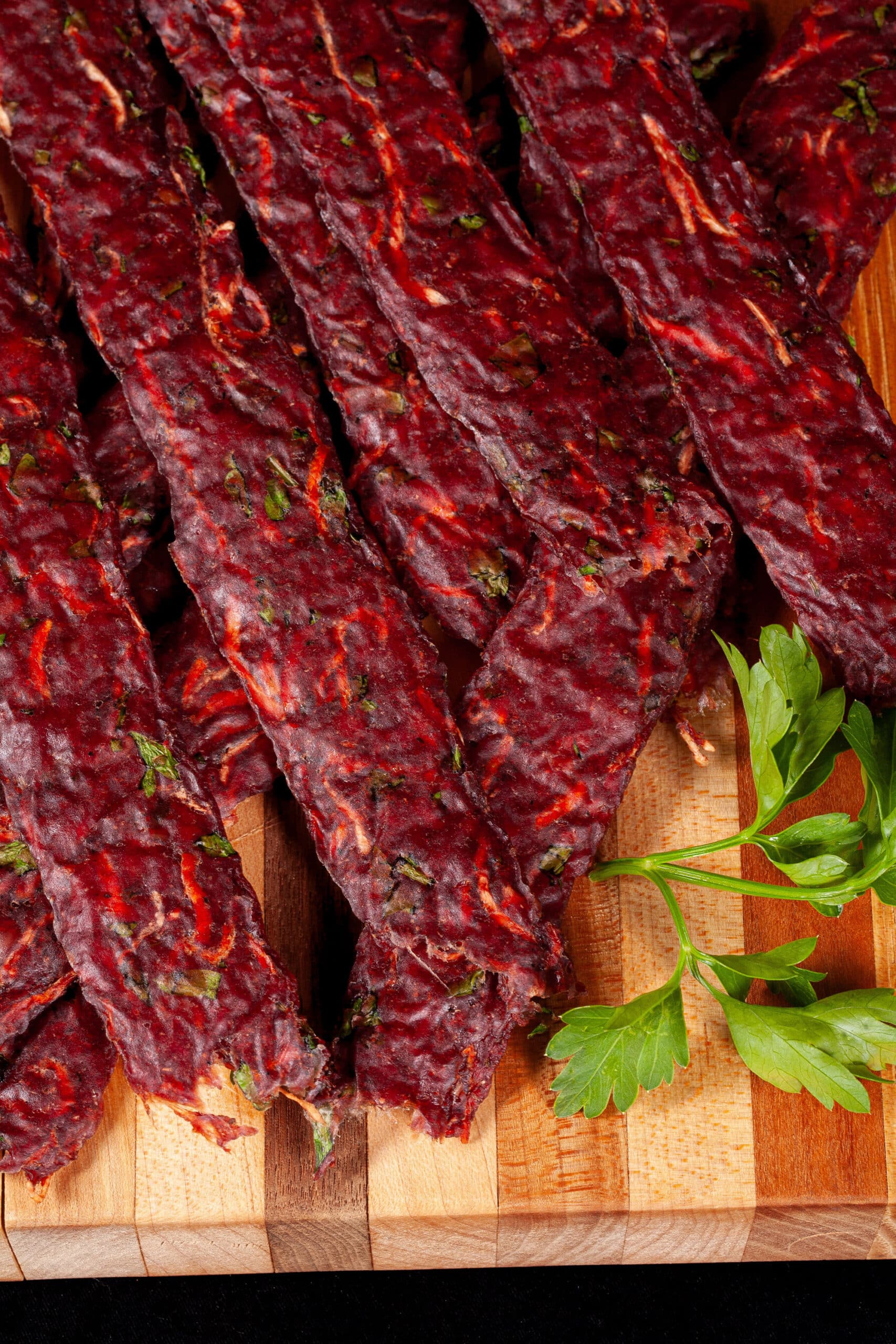 Several strips of Irish Stew jerky on a cutting board, with carrots, turnips, and parsley visible in the homemade beef jerky.