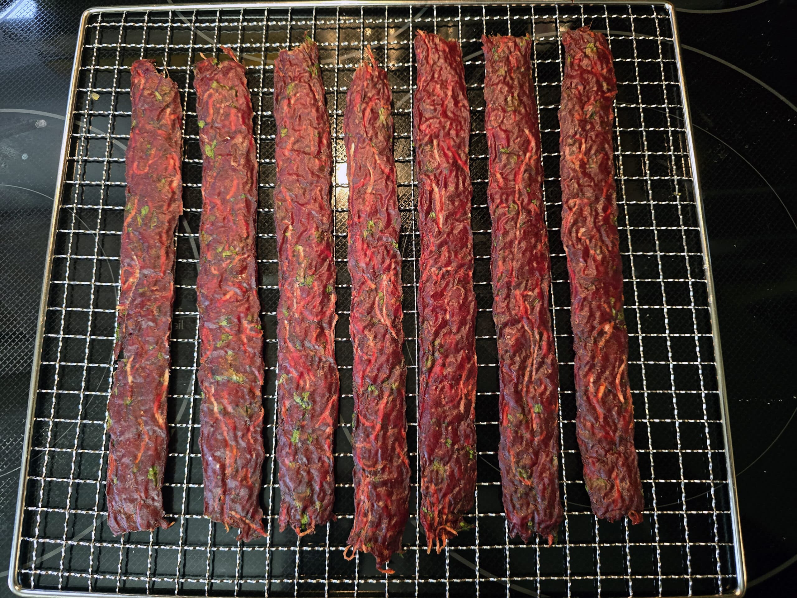 Several strips of finished Irish Stew Jerky on a rack.